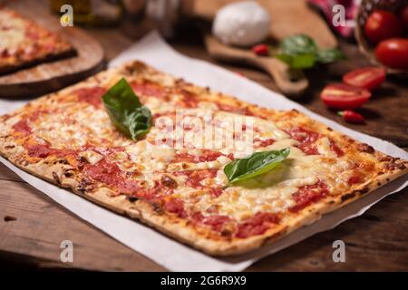 Rechteckige Form hausgemachte Pizza auf rustikalem Tisch mit Mozarella-Tomaten und Basilikum aus der Nähe Stockfoto