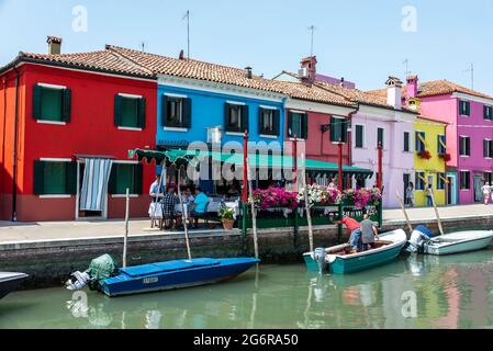 Ein belebtes Restaurant neben einem Kanal im kleinen Fischerdorf und kleinen Hafen von Burano, auf einer Insel in der Lagune von Venedig, etwa 7 km von Venedig i entfernt Stockfoto