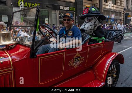 New York, Usa. Juli 2021. Während der Ticker Tape Parade der „Hometown Heroes“ in New York City fährt ein Hundefeuerwehrmann mit einem alten FDNY-Auto.im Canyon of Heroes in Manhattan werden Gesundheitsarbeiter, Ersthelfer und wichtige Mitarbeiter für ihren Dienst während der Covid-19-Pandemie geehrt. Kredit: SOPA Images Limited/Alamy Live Nachrichten Stockfoto