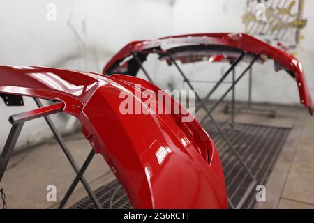 Roter Kunststoff-Autostoßfänger trocknet nach dem Lackieren in der Spritzkabine Stockfoto