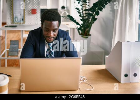 Young Business african Mann arbeitet an Laptop-Computer im modernen Büro - Fokus auf Gesicht Stockfoto