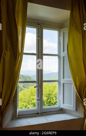 Fenster von innen gesehen auf einer grünen und romantischen Landschaft. Konzeptuelle Fotografie schaut weg Stockfoto