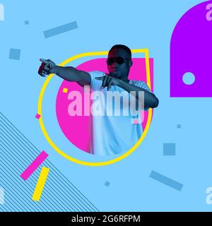 Phantasie und Kreativität. Zugeschnittenes Bild eines jungen hübschen afrikanischen Mannes in gelbem Rahmen auf rosa und blauem Hintergrund. Stockfoto