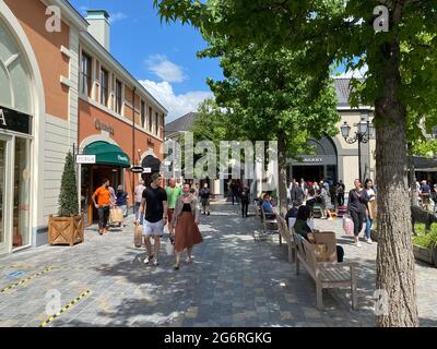 Roermond (Designer Outlet), Niederlande - 1. Juli. 2021: Blick auf die Einkaufsstraße mit Geschäften und Menschen, die im Sommer spazieren gehen Stockfoto