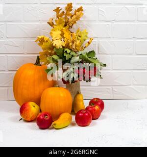 Stillleben mit reifen Kürbis, Äpfeln, Birnen und Herbstblättern auf weißem Grund. Nahaufnahme Herbst Ernte Hintergrund Stockfoto