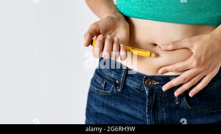 Injektion von Insulin in den Bauch einer Frau, Nahaufnahme. Diabetikerin, die Insulin-Stift verwendet, gibt sich Insulin-Injektion in ihren Bauch Stockfoto
