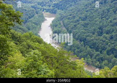 New River fließt durch den New River Gorge National Park mit White Water Rafts auf Stromschnellen und angrenzender Eisenbahn durch das Tal Stockfoto