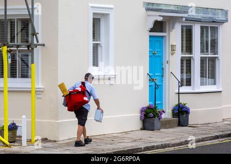 Ein Postbote oder Postbote, der eine Brieftasche mit sich trägt und Post in die englischen Häuser liefert Stockfoto