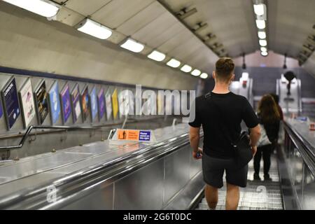 Ein erwachsener Mann, der auf einer Rolltreppe steht und zu einer u-Bahn-Station in london fährt Stockfoto