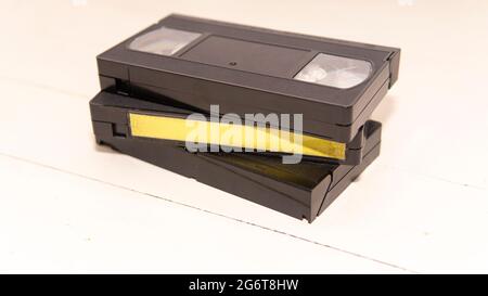 Ein Stapel von drei vhs-Bändern auf einer weißen Holzoberfläche. Einer von ihnen hat ein sauberes Etikett Stockfoto