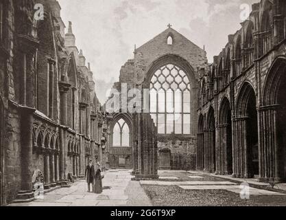 Ein Blick aus dem späten 19. Jahrhundert auf die Ruinen der Holyrood Chapel, die sich neben dem Palace of Holyroodhouse in Edinburgh, Schottland, befindet. Jetzt eine zerstörte Abtei der Kanonen regelmäßig in Edinburgh, Schottland. Die Abtei wurde 1128 von David I. von Schottland mit verschiedenen Zerstörungs- und Wiederaufbaurunden im Laufe der Jahrhunderte gegründet. Es wurde als Parlament von Schottland, als Ort von Krönungen, königlichen Hochzeiten und als Ort von königlichen Gräbern genutzt. Während eines Sturms im Jahr 1768 stürzte das Dach ein und ließ die Abtei als malerische Ruine zurück. Stockfoto