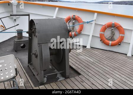 Anker-Ausrüstung auf Holzboardboden im Bug eines Touristen-Cruiser-Schiffes in weiß lackiert befestigt. Auf dem Hauptwetterunterdeck ist auch ein doppelter Poller installiert. Stockfoto