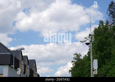 CCTV-Kamera, die an einem Metallmast befestigt ist, der aus Sicherheitsgründen in einem Wohnviertel installiert ist. Es gibt Himmel auf dem Hintergrund und eine Menge Kopierer-SPAC Stockfoto