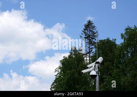 CCTV-Kamera an einem Metallmast mit Nadelbäumen und Himmel im Hintergrund und viel Kopierraum befestigt. Es dient dem Schutz des Eigentums. Stockfoto