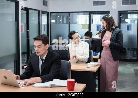 Die asiatische Managerin lobte und gratulierte der schwulen Mitarbeiterin, die im Büro erfolgreich arbeitet Stockfoto