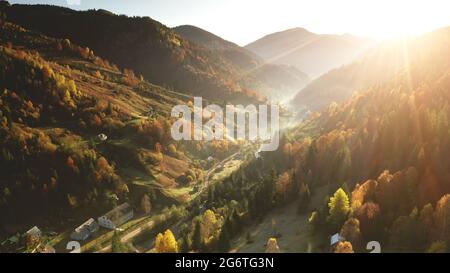 Luftiger Nebel über dem Bergdorf am Sonnentag. Herbst niemand Natur Landschaft. Hütten auf Mount Hills. Grüne Pinien Wald an der Landstraße im Nebel. Unbekannte neblige Karpaten, Ukraine, Europa Stockfoto