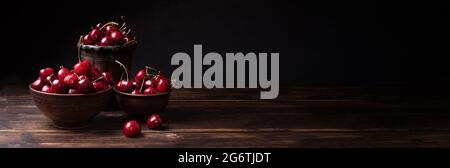 Banner, frische reife Süßkirschen in Schüsseln auf dunklem Grund, Sommerbeeren, Nahaufnahme. Stockfoto