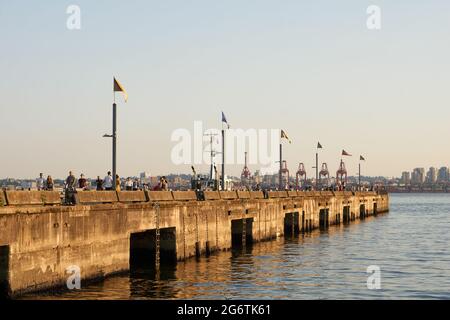 Menschen, die auf dem Burrard Dry Dock Pier am Wasser im Norden von Vancouver, British Columbia, Kanada, spazieren gehen Stockfoto