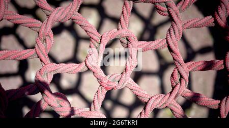 Detail eines roten und schmutzigen Sandnetzes auf einem sandigen Boden mit Schatten auf den Boden geworfen Stockfoto