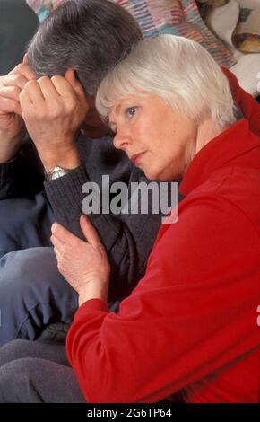 Reife Frau tröstet ihren verzweifelten Partner Stockfoto