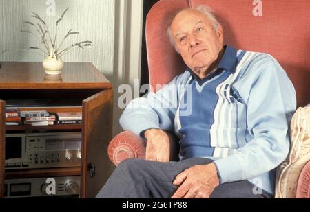 Besinnlicher älterer Mann, der in einem Sessel neben dem Audiosystem sitzt Stockfoto