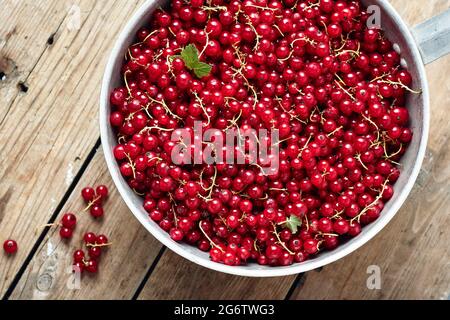 Rote Johannisbeeren in einer Schüssel auf einem Holztisch, Draufsicht. Stockfoto