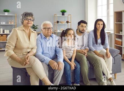 Eine Familie mit mehreren Generationen, die zu Hause auf der Couch sitzt und gemeinsam Fernsehen sieht Stockfoto
