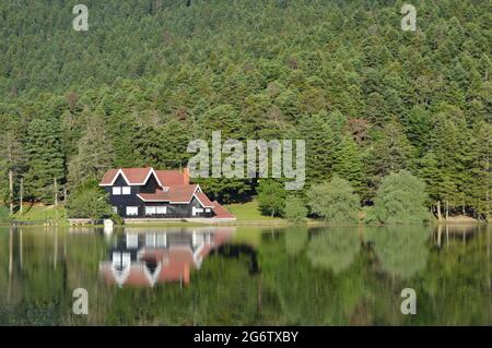 Der See im Wald im Bolu Gölcük Nationalpark und das Holzhaus am See, Spiegelung von Bäumen und Holzhaus im Wald am See Stockfoto