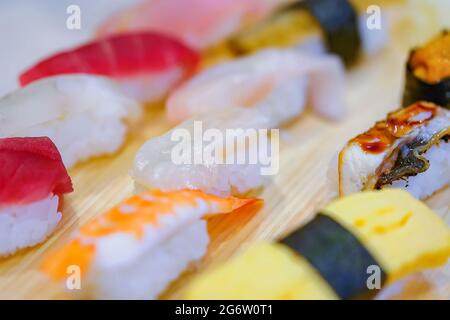 Nahaufnahme verschiedener Reisstücke, handgepresstes Nigirizushi oder Sushi mit Meeresfrüchten, einschließlich japanischer Anago-Congridae, vom Tamagoyaki gegrilltem Ei, ebi-Shrim Stockfoto