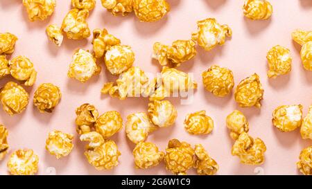 Karamellfarbenes Popcorn auf pastellrosa Hintergrund. Stockfoto