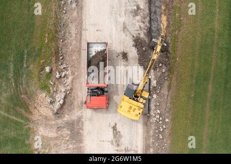 Bagger graben Boden in der Nähe des Feldes und Verladung auf den LKW Stockfoto