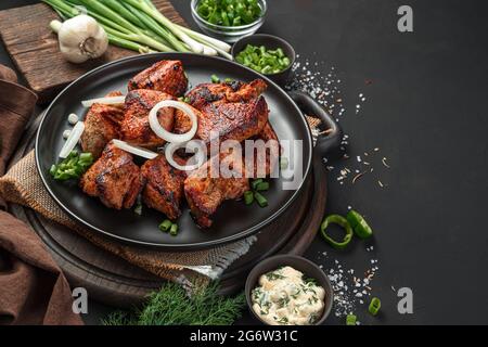 Kebab auf einer Platte mit Zwiebeln auf schwarzem Hintergrund schälen. Fleischgericht. Seitenansicht, Nahaufnahme. Stockfoto