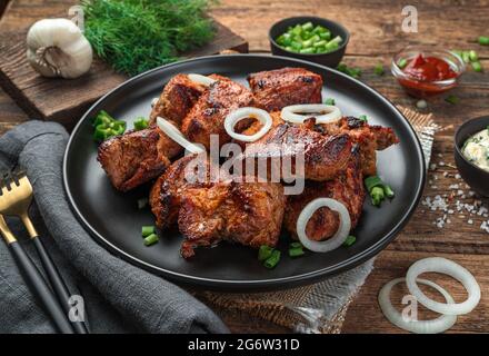 Gegrilltes Fleisch, Barbecue, Kebab mit frischen Kräutern auf Holzgrund. Seitenansicht, Nahaufnahme. Stockfoto