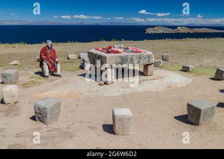 ISLA DEL SOL, BOLIVIEN - 12. MAI 2015: Der gebürtige Mann in traditioneller Kleidung neben dem Zeremonialtisch war wahrscheinlich der Ort menschlicher Opfer Stockfoto