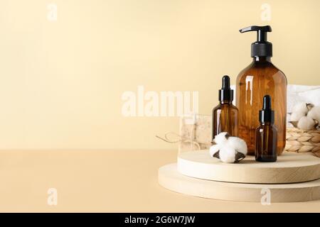 Moderne Komposition mit Naturkosmetik und ätherischem Öl mit dunkelbraunen Flaschen auf beigem Hintergrund. SPA-Set für die Körperpflege. Speicherplatz kopieren. Stockfoto