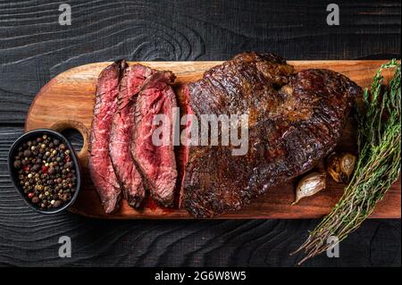 Gegrilltes Metzgerfleisch Choice Steak Onglet Aufgehängtes Rinderfleisch auf einem Schneidebrett. Schwarzer Holzhintergrund. Draufsicht Stockfoto
