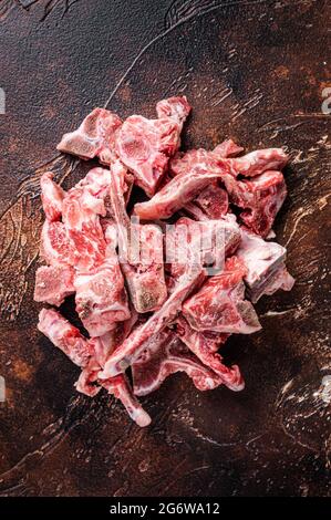 Rohes Fleisch auf den Knochen gewürfelt zum Eintopf. Dunkler Hintergrund. Draufsicht Stockfoto