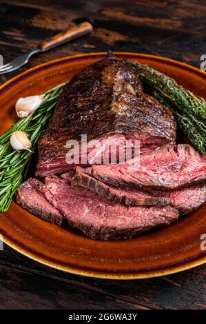 Gerösteter Aufhänger oder Onglet-Rinderfleischsteak in Scheiben auf einem rustikalen Teller mit Hackschnitzel. Dunkler Holzhintergrund. Draufsicht Stockfoto