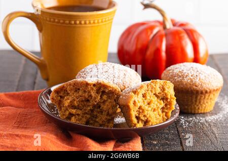 Kürbis Gewürz Muffins gekrönt mit Puderzucker auf einem rustikalen Holztisch Stockfoto