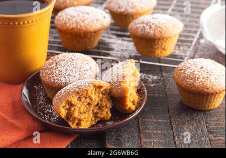 Kürbis Gewürz Muffins gekrönt mit Puderzucker auf einem rustikalen Holztisch Stockfoto