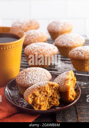 Kürbis Gewürz Muffins gekrönt mit Puderzucker auf einem rustikalen Holztisch Stockfoto