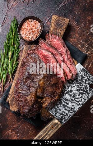 Gebratenes, hängendes, zartes oder in Scheiben geschnittenes Rindersteak auf einem Fleischbrett mit Hackschnitzel. Dunkler Hintergrund. Draufsicht Stockfoto