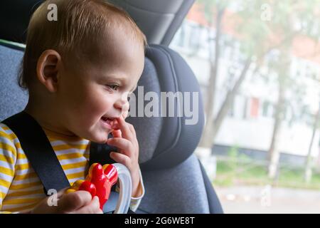 Glückliches Baby, das auf dem Autositz sitzt und spielt. Stockfoto