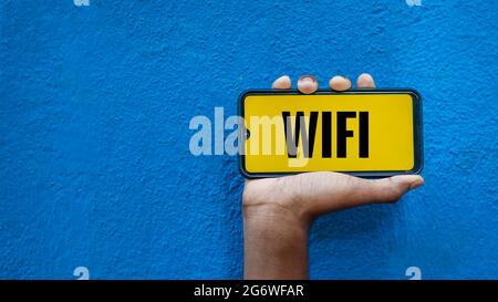 WiFi-Wort auf Smartphone-Bildschirm isoliert auf blauem Hintergrund mit Platz für Text kopieren. Wireless Fidelity. Stockfoto