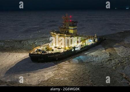 Sabetta, Region Tjumen, Russland - 04. Dezember 2020:der Eisbrecher liegt nachts im Eis. Der Eisbrecher leuchtet mit allen Lichtern. Stockfoto