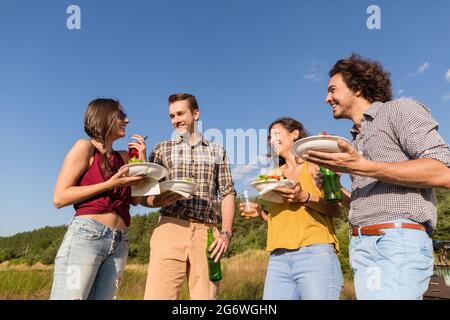 Freunde bei der Grillparty in der Natur trinken Bier und Essen Hamburger Sandwiches Stockfoto