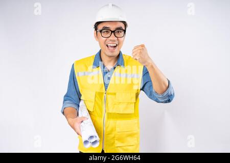 Lächelnder junger asiatischer Bauingenieur mit Helm-Hut auf isoliertem weißem Hintergrund. Mechaniker-Servicekonzept. Stockfoto