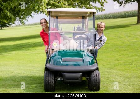 Portrait von glückliches junges Paar in der Golfkarre sitzen peeking Stockfoto