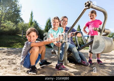 Mutter und Kinder im Sandkasten spielen mit Digger Stockfoto