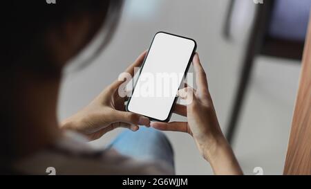 Zugeschnittene Aufnahme eines Mädchens, das ein Mobiltelefon mit leerem Bildschirm verwendet Stockfoto